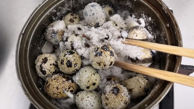 盐焗鹌鹑蛋,冷却后,用筷子,小心的把鹌鹑蛋,从盐里面戳出来,因为盐现在有点硬,要让它松动一下