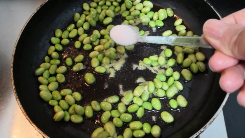 雪菜炒毛豆,毛豆翻炒至,变色断生后,加入盐
