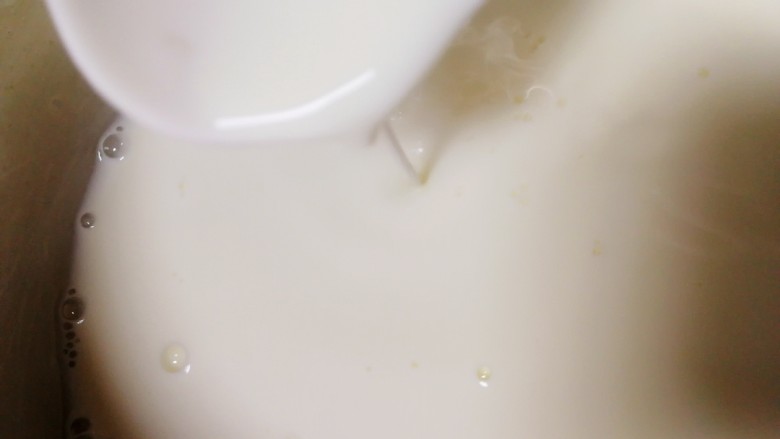 椰奶小方【零失败】,把牛奶玉米淀粉液一点一点加入热奶锅里,不断搅拌推动奶锅底部。