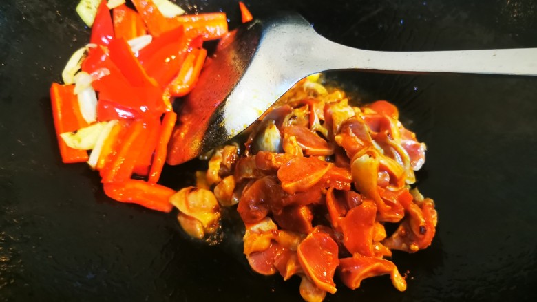 酸豆角辣炒鸡胗,红辣椒、姜蒜搁置锅里一侧,大火底油加入腌制好的鸡胗爆炒