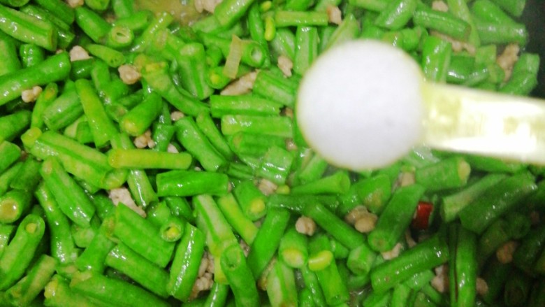 肉沫豇豆,豇豆变色、稍变软,加入适量盐。之后可以点入一点儿水,稍焖炒几下。这样豇豆熟得比较快。