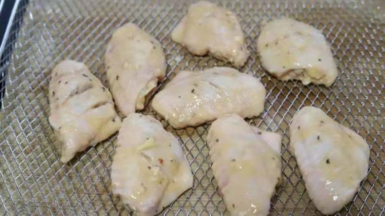 美味的法式黑椒烤鸡翅,将腌制好的鸡翅取出来,均匀的挂上一层稀面糊,放入烤箱的空气炸烤网上。生姜这时可以丢弃不要