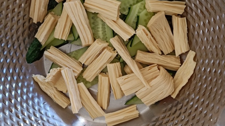 凉拌腐竹黄瓜,准备一个略微大一点的容器,黄瓜片和腐竹倒进容器中。