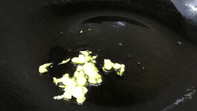 青椒炒口蘑,热锅倒入适量油,油温热放入蒜末炒香。