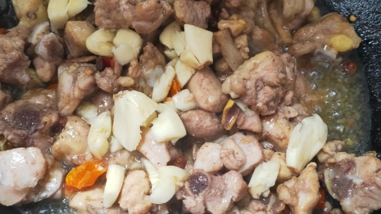 青椒鸡腿盖饭,煸炒两分钟后放入大蒜,然后加半瓶盖料酒(就是料酒瓶子的盖),盐,生抽,老抽,鸡精调味