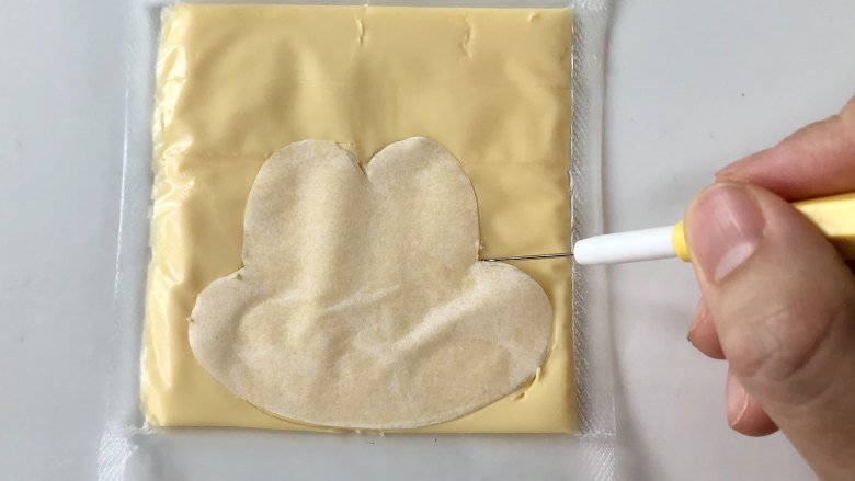 萌萌的米奇与米妮便当,在家感受迪士尼,用烘焙纸叠着稿纸上的造型剪出米奇的脸部,然后贴在<a style='color:red;display:inline-block;' href='/shicai/ 62159'>芝士片</a>上,用翻糖针(或牙签)刻出脸部的形状。
