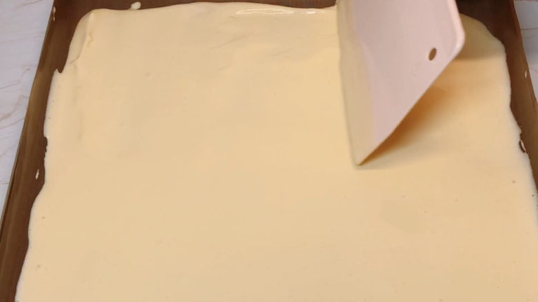 虎皮蛋糕卷,倒入铺好油布的烤盘中,用刮刀抹均匀