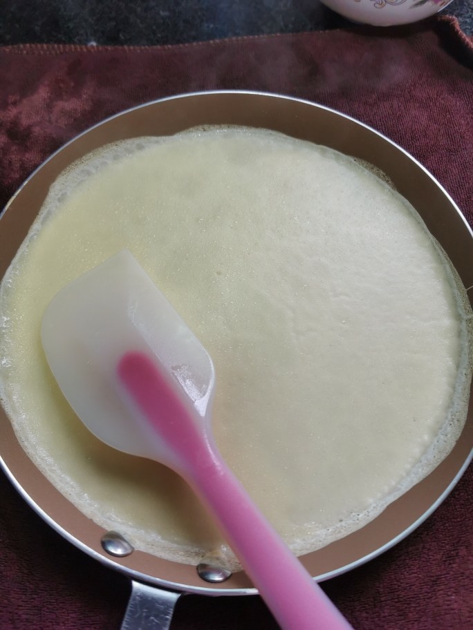 榴莲千层蛋糕,看到蛋液凝固了,表面稍微有点起泡就好了,不要煎过头,煎糊了就不好看了
为了更快可以拿出来,就先铺个湿毛巾,把平底锅放在湿毛巾上5秒左右降温,再用硅胶刮刀轻轻挑起蛋皮边就可以轻松拿起来了