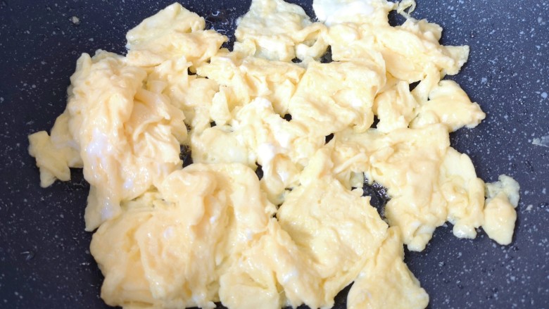 白玉菇炒鸡蛋,待蛋液底部凝固以后用铲子轻轻推动翻炒,炒熟的鸡蛋盛出备用。
