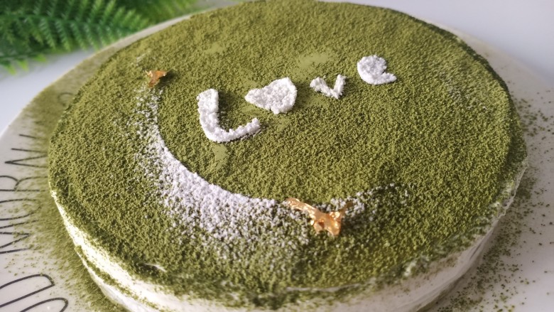 抹茶千层蛋糕,取出蛋糕,表面撒一层抹茶粉,中间吊坠两块金箔装饰
