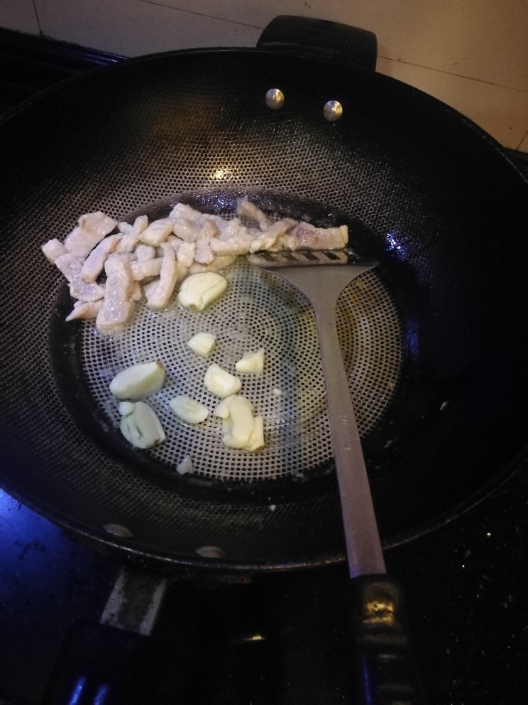 四季豆炒肉丝,炒制猪肉变白,加入拍碎的蒜,翻炒。