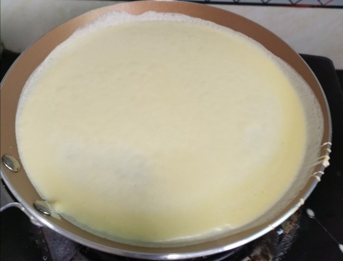 榴莲千层蛋糕, 煎蛋皮全程小火煎,不需要放油,因为蛋液里加了黄油,不会粘锅,锅烧热后离火倒入一勺蛋液后转一圈,让蛋液均匀铺开,再把锅放到火上煎