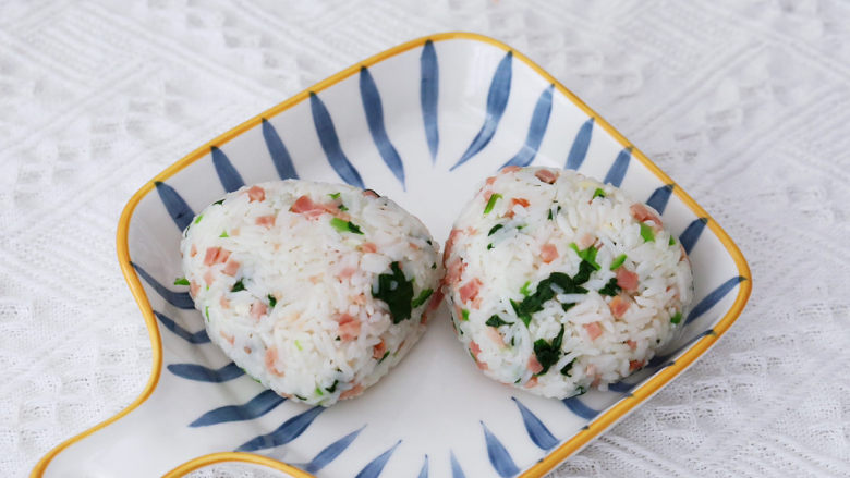 培根青菜烤饭团,利用保鲜膜包起来攥紧,再整理成三角形状,排放入烤盘中