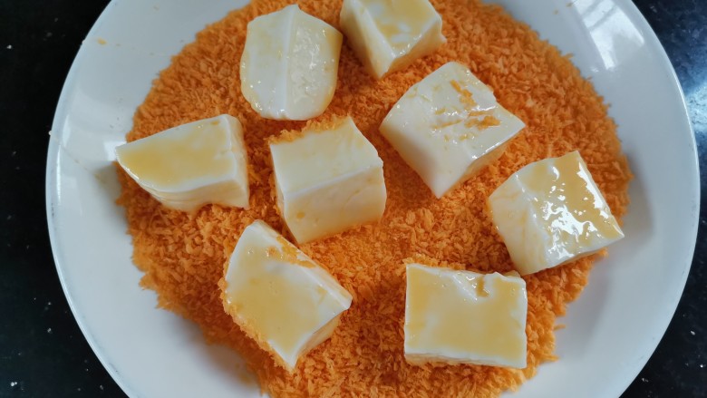 炸奶冻,裹好蛋糊的奶冻放入面包糠里