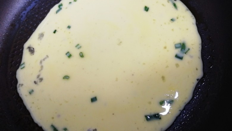 家常鸡蛋饼,倒入蛋液,转动平底锅,使蛋液均匀铺开,成圆形。