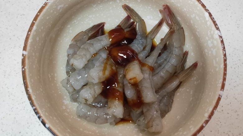 黄金土豆虾球,把剥好的虾倒入碗中再依次放入耗油,酱油,盐,胡椒粉