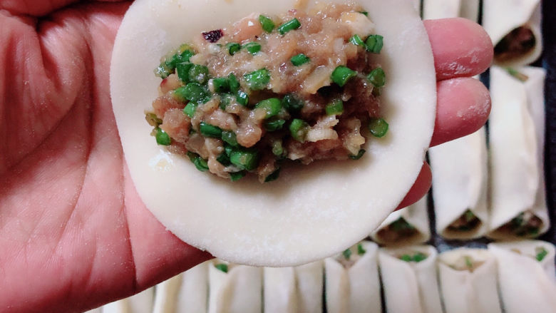 韭菜锅贴,准备好饺子皮,包入肉馅。