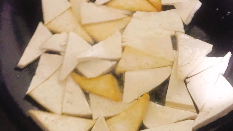 家常烧豆腐,隔几秒钟用铲子翻面,部分豆腐一面已经煎金黄了,仍需继续小火慢慢煎,勤翻面,直到全部都是两面金黄色
