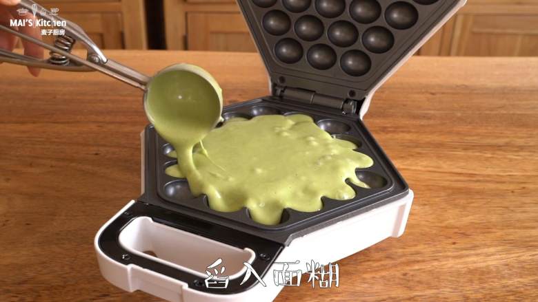 抹茶红豆控必做【抹茶红豆鸡蛋仔】,鸡蛋仔机预热完成后,刷适量食用油,舀入约100g面糊(麦子厨房挖球勺2勺半),让面糊流至每个鸡蛋仔孔内。