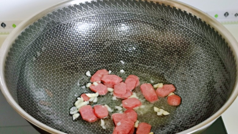 红烧素鸡,起油锅,加入蒜炒香,再加入香肠片翻炒。