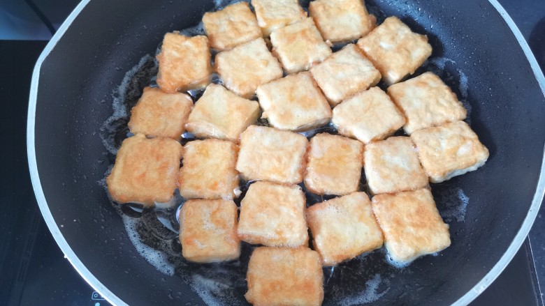 家常烧豆腐,锅里倒入适量的油,油热放入豆腐煎至两面金黄