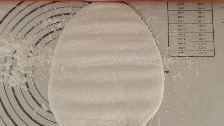 可以撕着吃的呛面大碱馒头,然后开始叠面。把面用粗的擀面杖按压成饼,撒一层面粉