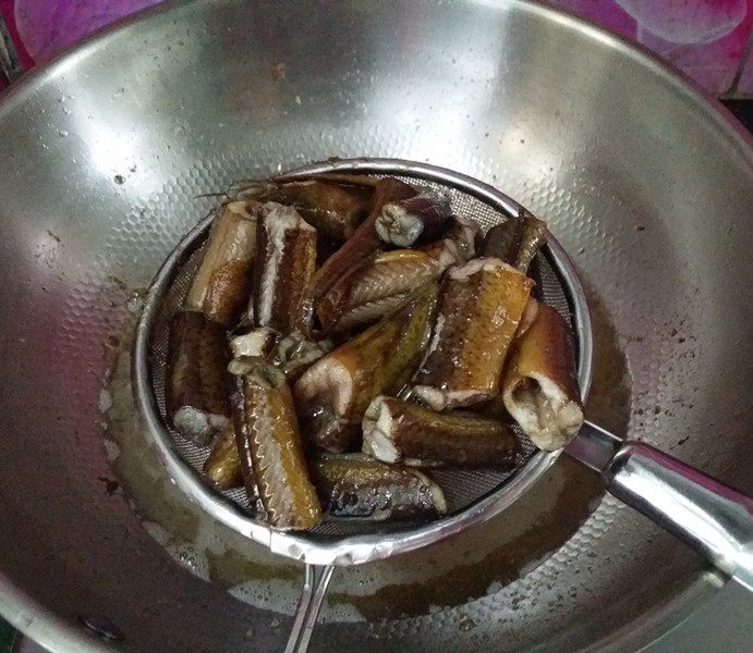 红烧黄鳝,待鳝鱼变色且开始弯曲时,再用铲子推一推,就会自动分开了,然后用漏勺捞出备用