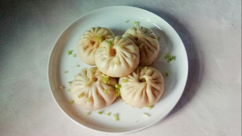 牛肉圆葱生煎包,装入盘中,撒上葱花。
