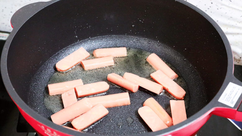 香辣孜然火腿肠炒年糕,锅中倒入适量的食用油烧热,放入火腿肠煎至表面金黄色