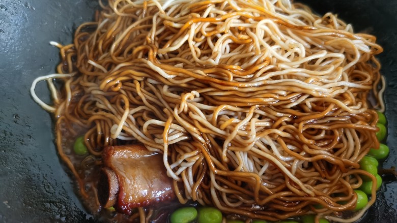 排骨焖面,其间打开锅盖,用筷子翻动一下面条,根据锅里汤汁的情况,分次加入盛出来的排骨汤。再盖上锅盖焖至汤汁收干面条成熟,时间根据面条的粗细决定。