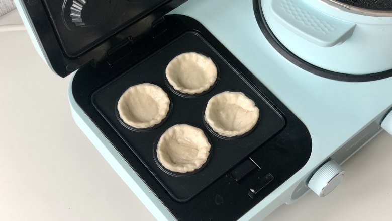 手抓饼变身小巧可爱的水果挞,东菱三明治机装好果挞盘,预热2分钟,然后把手抓饼胚放进去。