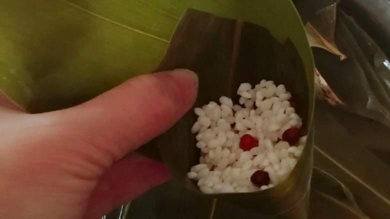 红豆粽子,先放入一颗红枣,再放一层红豆糯米。