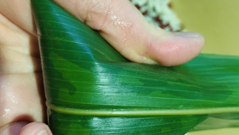红豆粽子,上面的剩余粽叶往下压,并捏紧两边