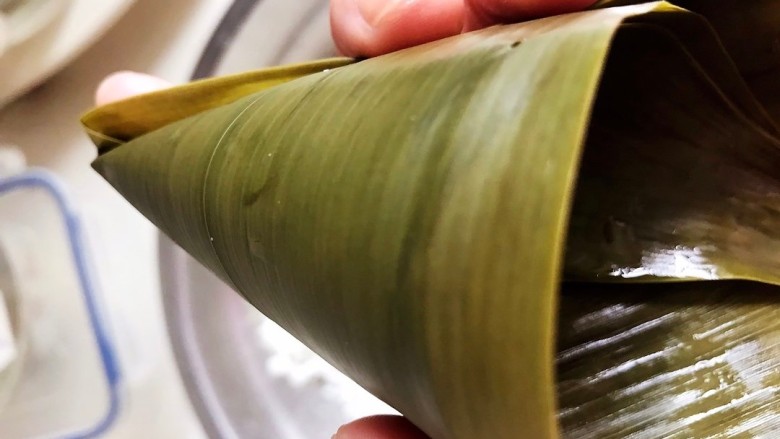 红豆粽子,粽叶煮软后,将粽叶折成三角