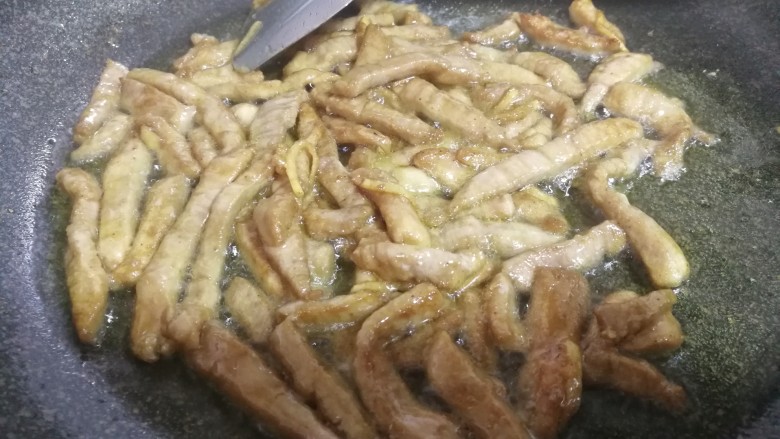 肉炒蒜苔,慢慢煸炒肉条变色微微金黄。