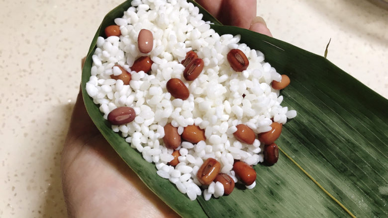 红豆粽子,最后再舀适量糯米红豆,盖住蜜红豆,装满漏斗