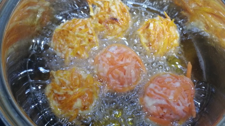炸胡萝卜丸子,炸至一面定型金黄后,翻面。