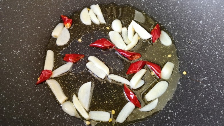 清炒莴笋丝,炒锅内倒适量的食用油烧热,下入蒜片和干红辣椒炒香。