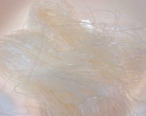 粉丝蒸瑶柱,龙口粉丝2把,开水烫软泡五分钟后捞出。
加香油少许将粉丝拌匀,这样蒸好后粉丝就不会坨在一起。