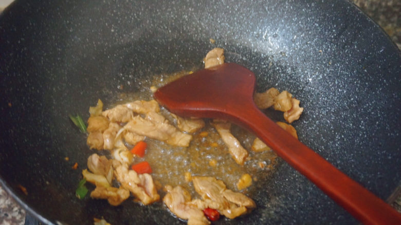 四季豆炒肉,锅内热油下锅,倒入蒜泥和红米椒翻炒肉片