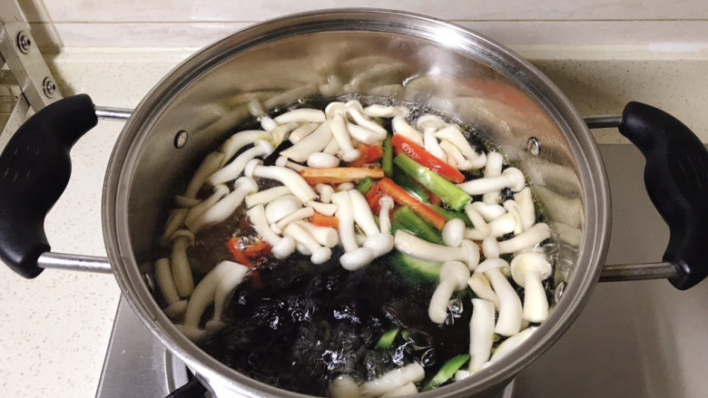 白玉菇炒肉,水中加一勺盐,几滴食用油,大火烧开,按顺序下白玉菇、木耳、青红椒,焯水两分钟