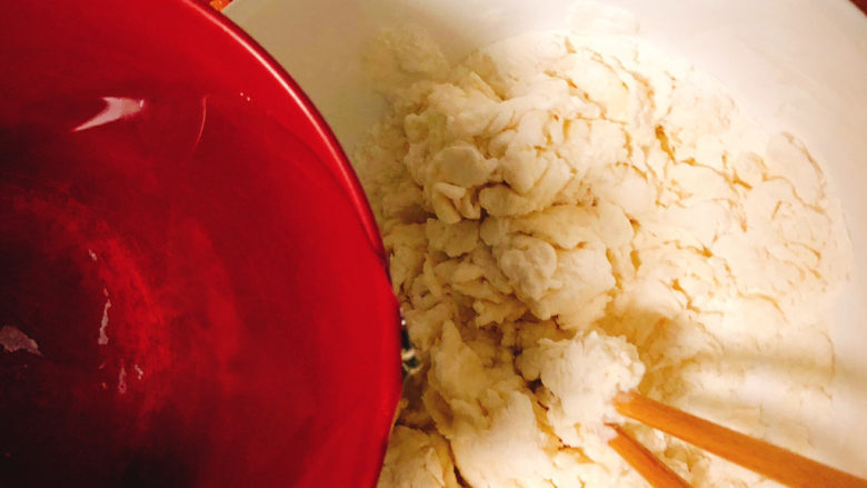 角瓜蔬菜瘦肉卷,普通<a style='color:red;display:inline-block;' href='/shicai/ 519'>面粉</a>中先倒入50克清水,边倒入边将食材搅拌成面絮状。