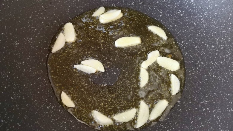 青椒炒素鸡,炒锅内倒适量的食用油烧热,下入蒜片炒香。