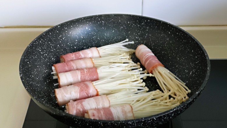 金针菇肥牛卷,平底锅中刷上食用油,摆入金针菇肥牛卷。(固定好后可以将牙签取下来,收口朝下煎)
