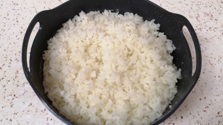 芝士焗饭,时间到米饭已经蒸好了,将滤糖甑从电饭煲里面取出,用铲子翻动米饭散一下热气。