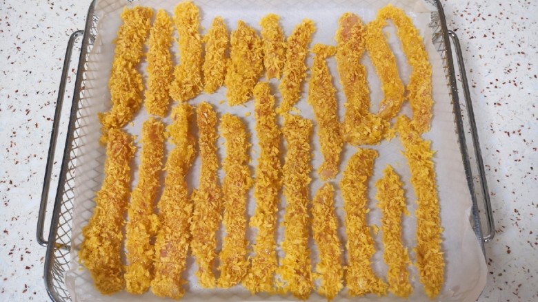 香酥鸡柳,炸篮里铺上油纸,放上做好的鸡柳。