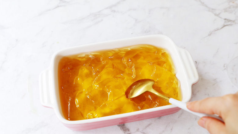蜜桃乌龙茶冻撞奶,将凝固的茶冻用勺子勺碎,越碎越好,碎一点就可以直接用吸管吸着喝了