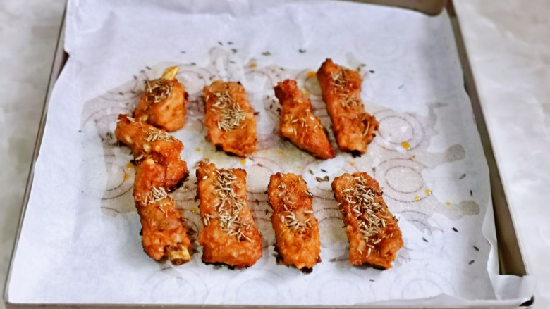 孜然排骨,20分钟后取出烤盘,撤掉锡纸,再铺上油纸,摆放上肋排,撒上<a style='color:red;display:inline-block;' href='/shicai/ 146573'>孜然粒</a>。