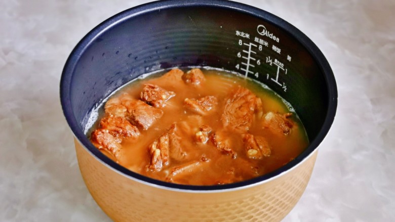 小米蒸排骨,再把煸炒过的排骨倒入电饭煲中,排骨铺平。