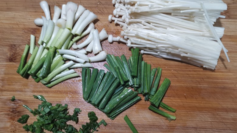 金针菇肥牛卷,把金针菇切去后面的根部。蒜切成段。根部比较难熟,分开来切。
